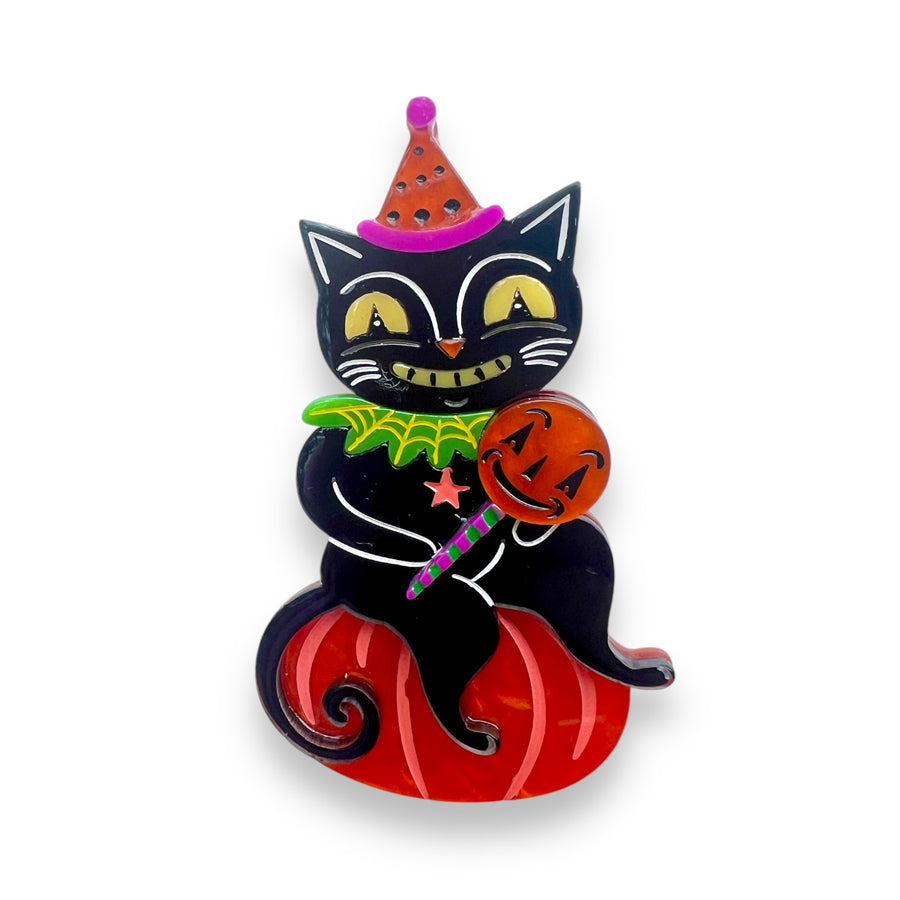 A black cat brooch with a party hat and holding a pumpkin, designed by Johanna Parker x Lipstick & Chrome.