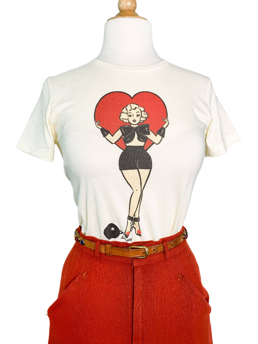 A fitted tee in ivory color with a digital print of a character standing inside a heart shape.