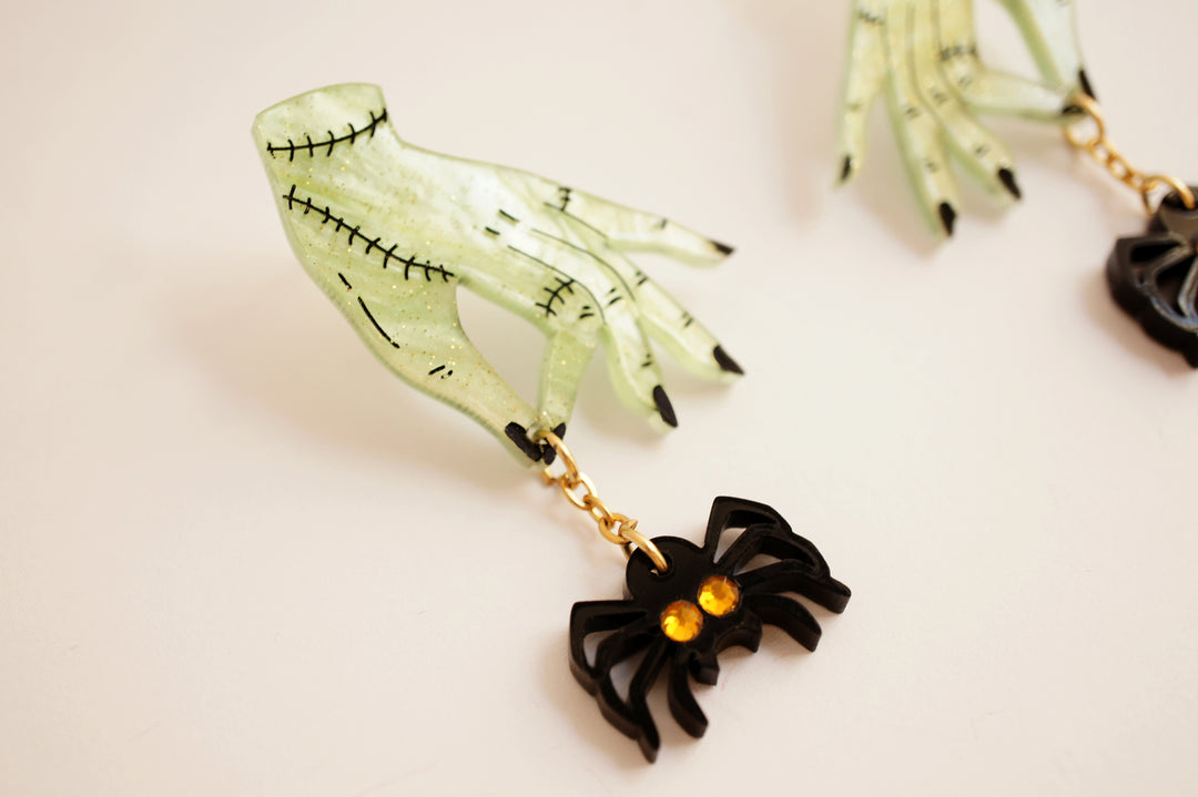 Zombie hands and spider earrings angle — acrylic horror statement jewelry — LaliBlue Midnight Cinema