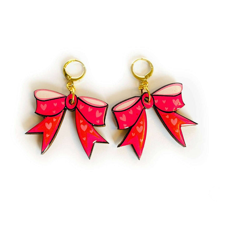 'The big statement bow earrings! go big!' Liven up your wardrobe with these cute illustrated bright pink bow earrings on huggie hoops. Illustrated with tiny pink hearts. Fabulous for summer and to accessories with any pink outfits. They shimmer with hard glistening resin. Truely statement pieces. Earring Basics * measurements 5cm x 5 cm * Bright pink design - illustrated by Rosie Parker * Gold huggie comfortable french hoops * Lightweight * Super cute gift idea! and for those who adore statement earrings
