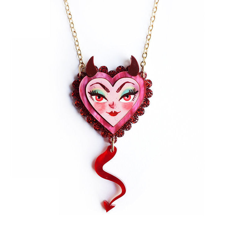 Heart-shaped pendant with a devil face design on a gold chain against a white background