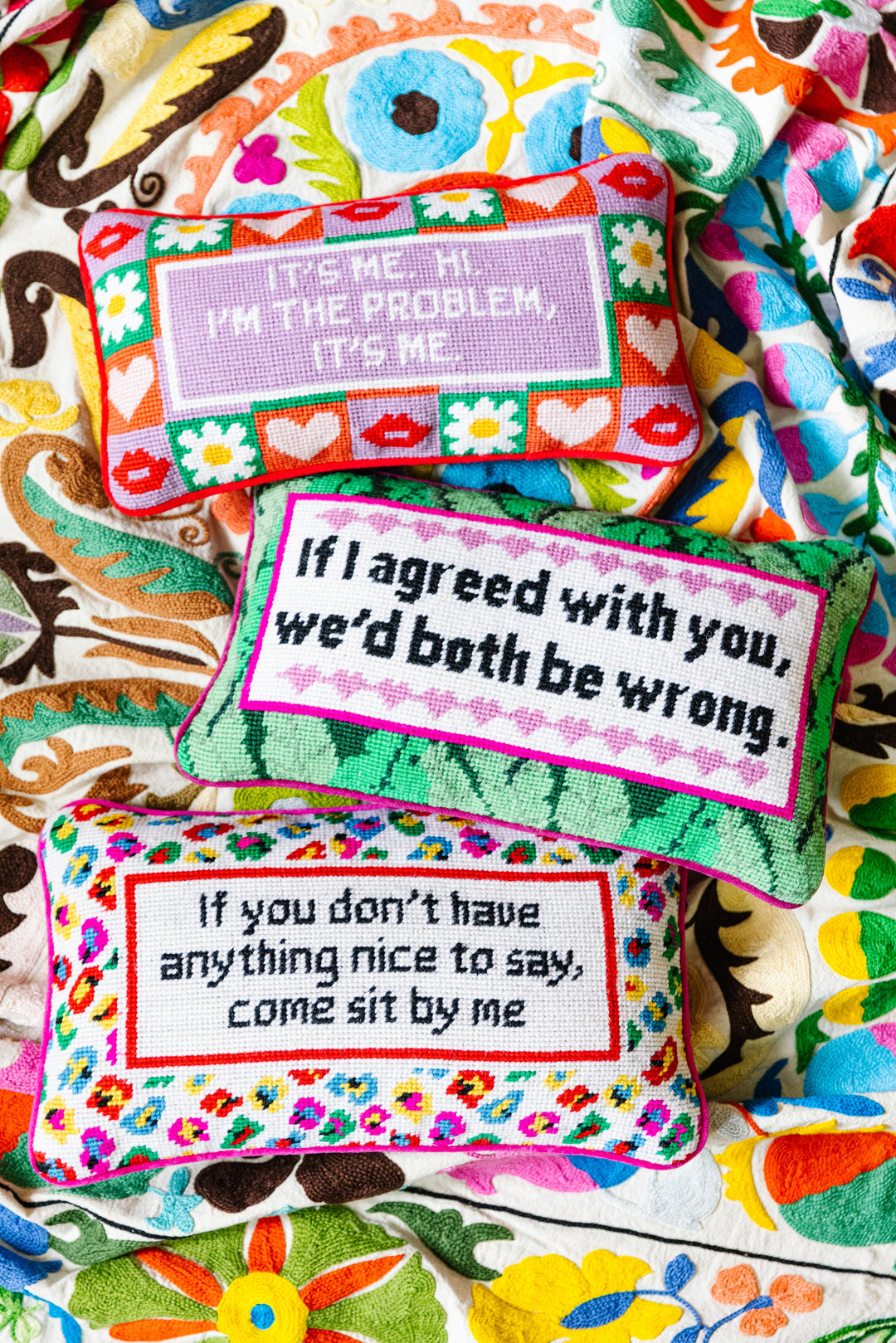 Colorful pillows with embroidered text on a patterned fabric background