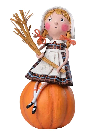 Decorative figurine of a girl sitting on a pumpkin with a broom, against a neutral background.