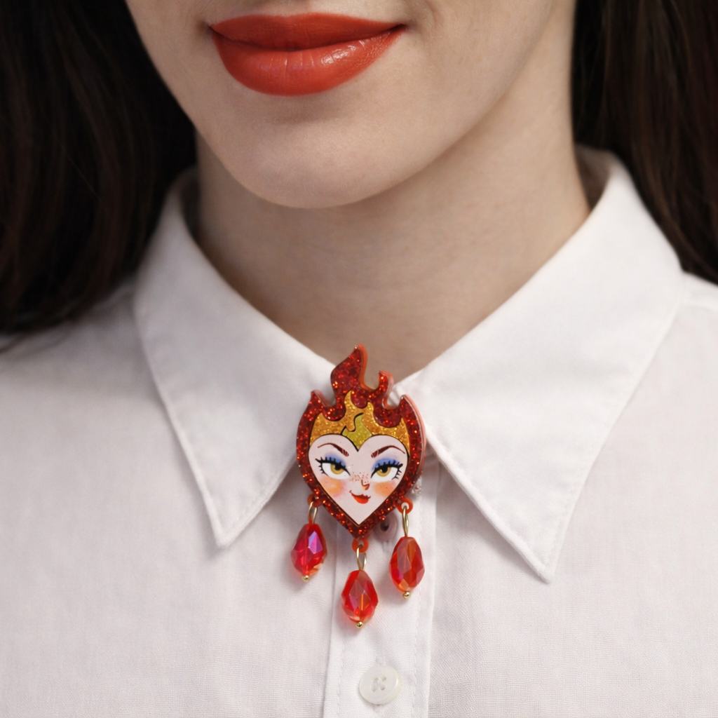 Close-up of a person wearing a white shirt with a decorative red and gold brooch.