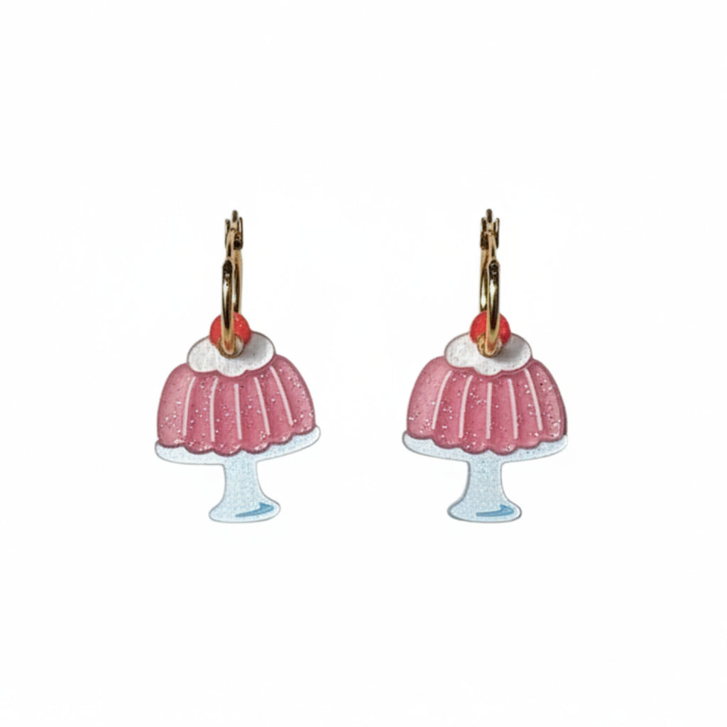 A pair of dangling jello mold earrings shaped like pink frosted cupcakes with gold-tone hooks and small red gem accents, shown on a plain white background.