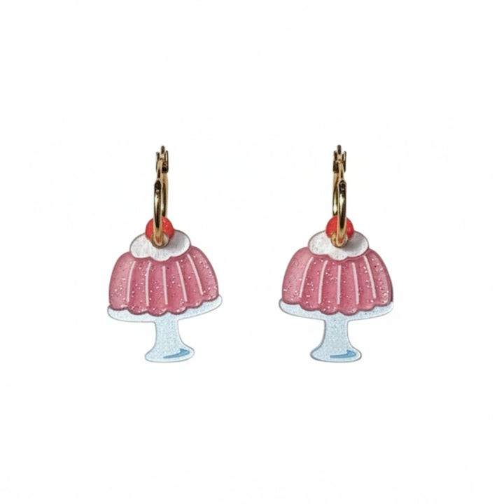 A pair of dangling jello mold earrings shaped like pink frosted cupcakes with gold-tone hooks and small red gem accents, shown on a plain white background.