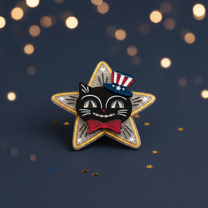 Star-shaped brooch with a black cat design wearing an American flag hat on a dark background.
