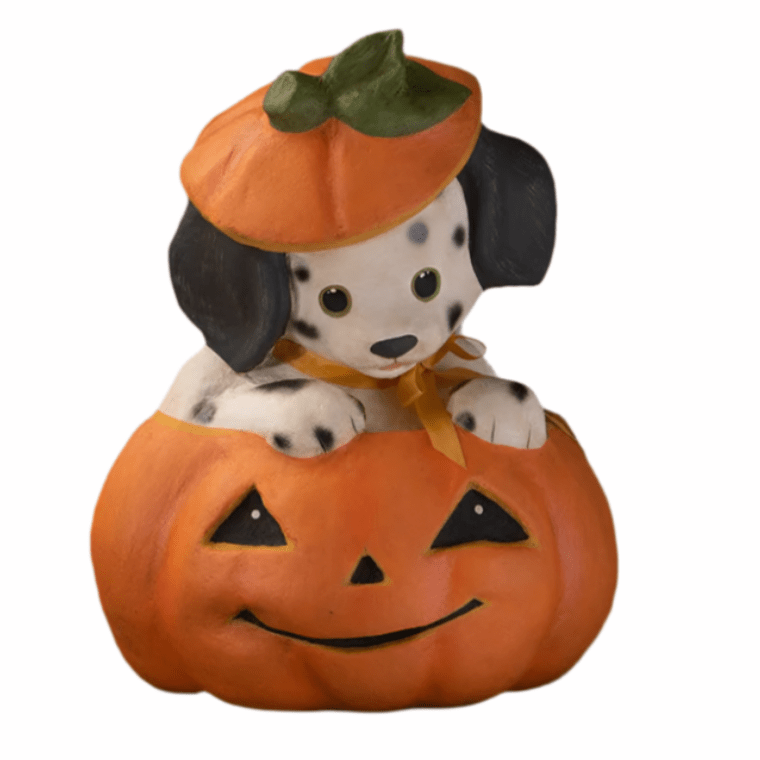 Dog figurine inside a pumpkin with a Halloween hat on a white background
