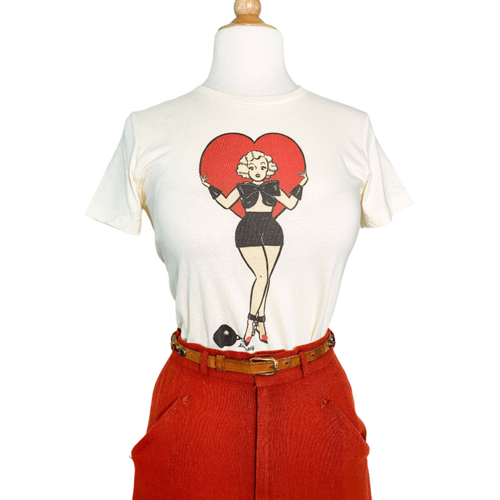 A fitted tee in ivory color with a digital print of a character standing inside a heart shape.