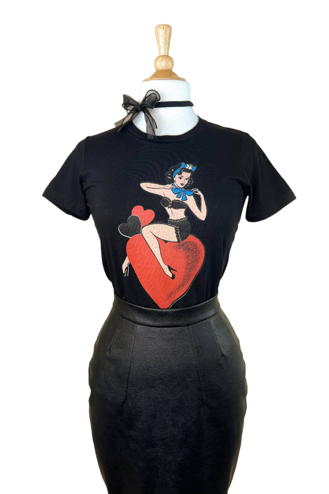 A black fitted tee with a graphic print of a person sitting on a heart and holding a microphone.