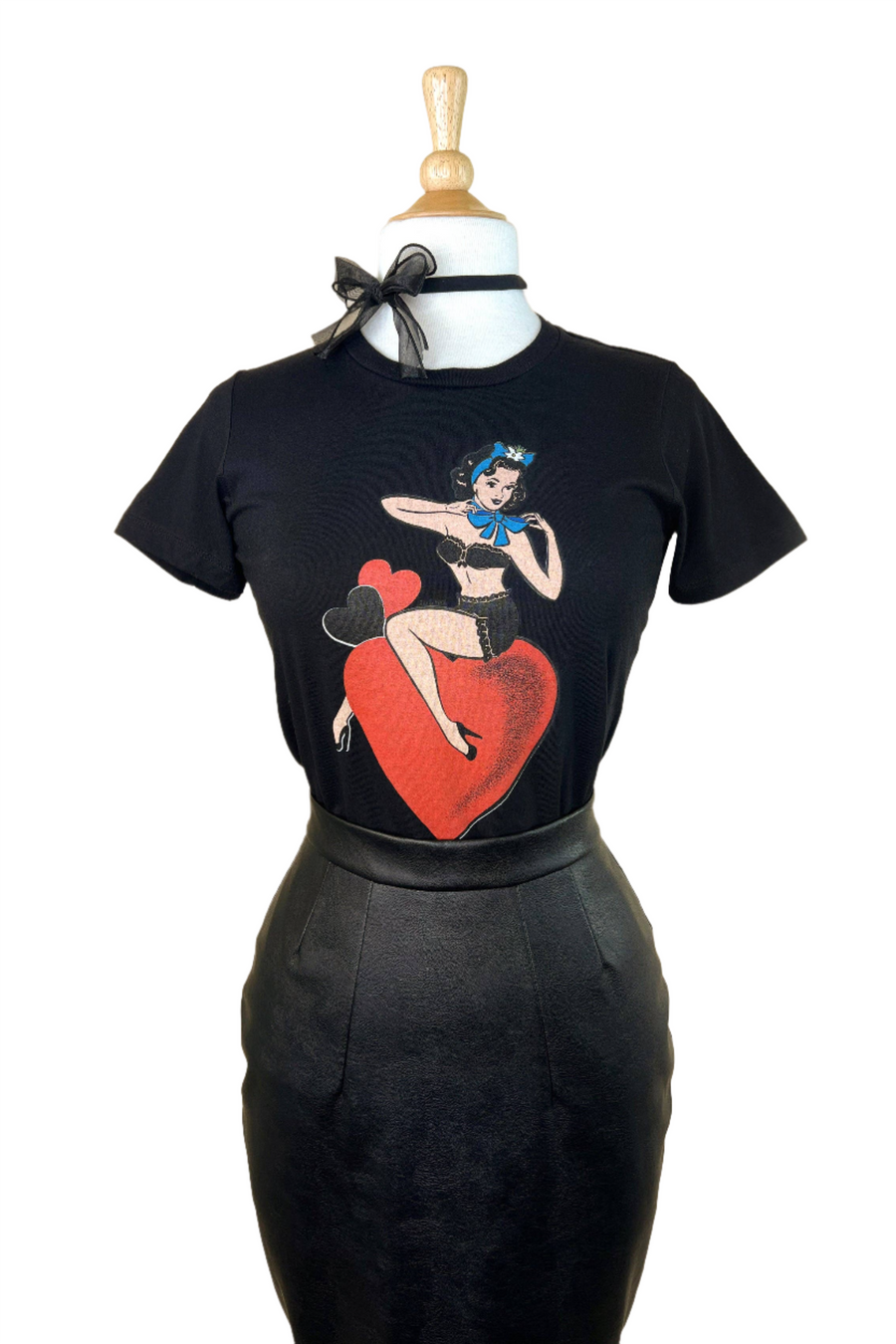 A black fitted tee with a graphic print of a person sitting on a heart and holding a microphone.