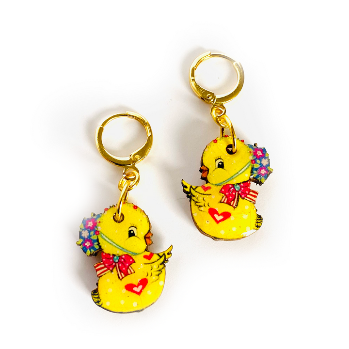 'Charlie the Chic drop earrings - with huggie hoops!' Cute Easter chic drop earrings featuring ducky the magical little baby chic. Beautifully illustrated in light in pastel and bright yellow. Incredibly comfy to wear, and beautifully made. Brighten up your easter with these special pieces of jewellery. Earrings basics * Measurement 6cm x 6xm * Bunny theme * Miss matched colours * Resin on woods creating a glass affect * Gold plated comfy huggie hoops * Perfect for day wear